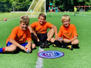 sb4u players sitting in front of an nycdc youth logo on a staten island soccer field